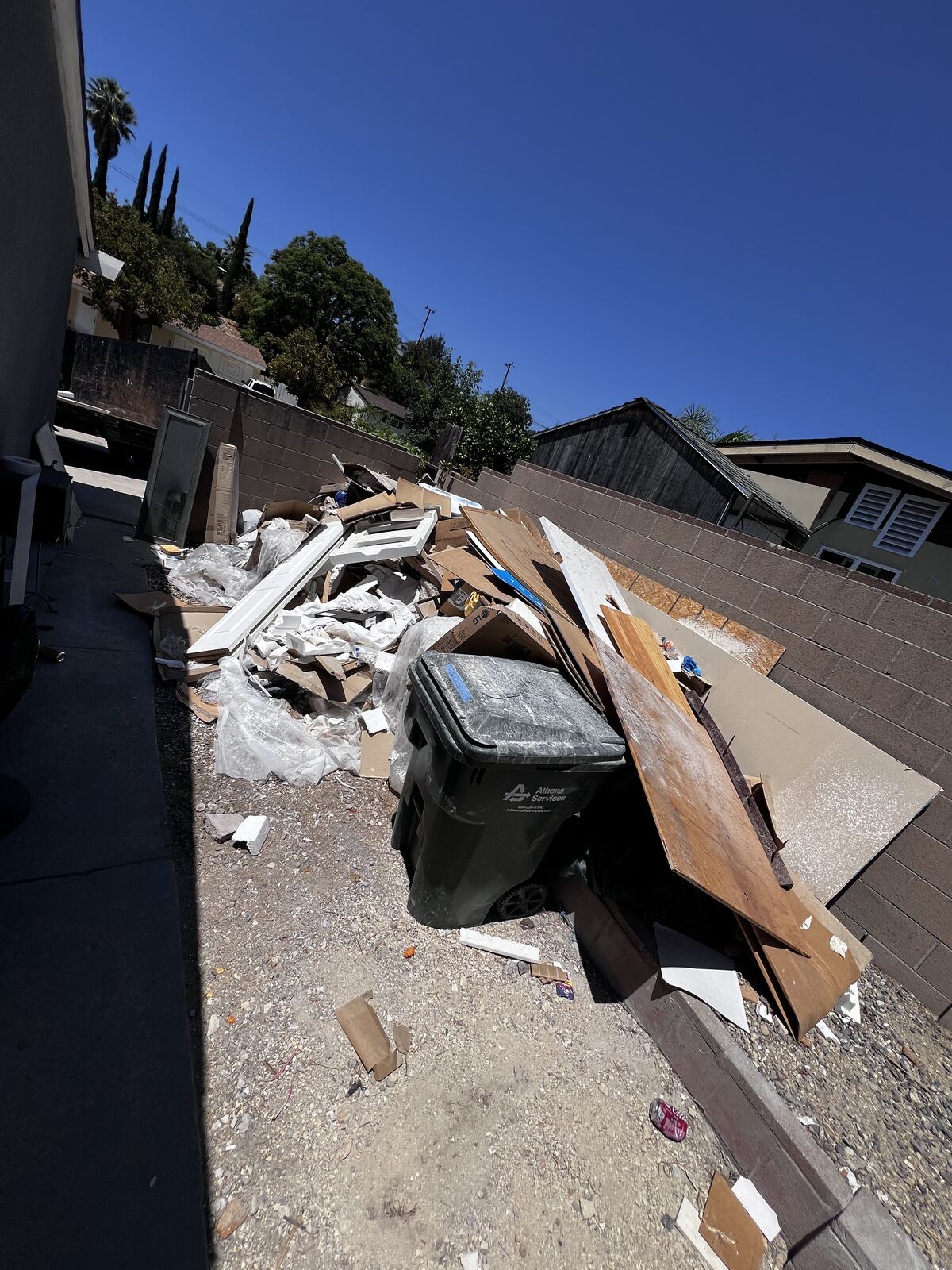 Side yard piled with construction debris and cardboard before cleanup